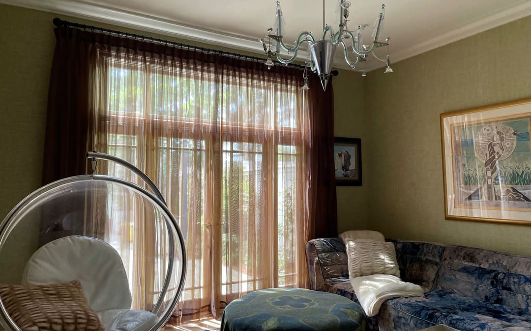 Custom sheer and drapery panels on a decorative rod in an Orange County living room, made by Capistrano Upholstery