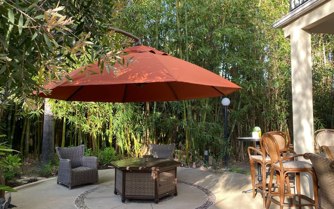 Patio in Orange County with a terracotta umbrella and wicker seating reupholstered in outdoor fabric by Capistrano Upholstery