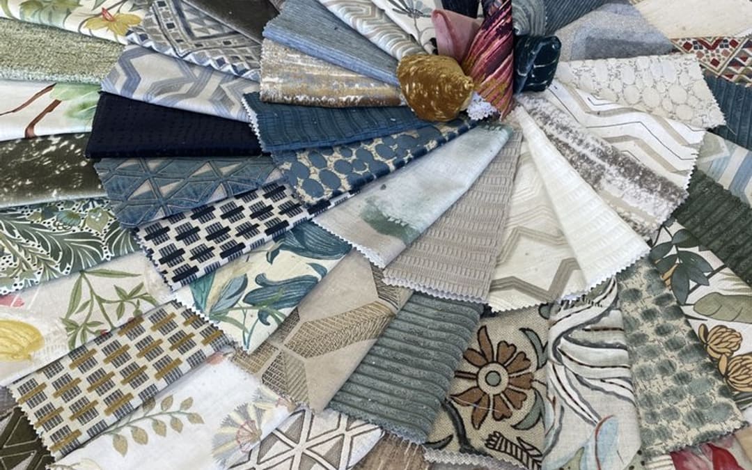 A fan of upholstery fabric swatches in linens, velvets, stripes and prints laid out in the Capistrano Upholstery shop