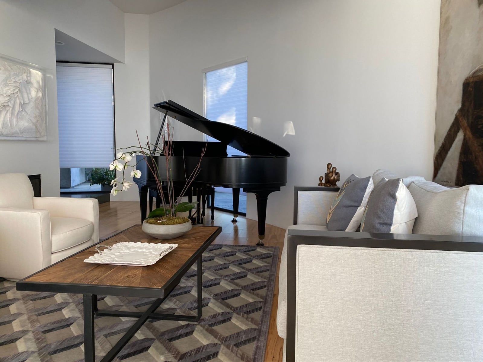 Living room with a grand piano, a cream swivel chair and a custom sofa in light linen with grey pillows
